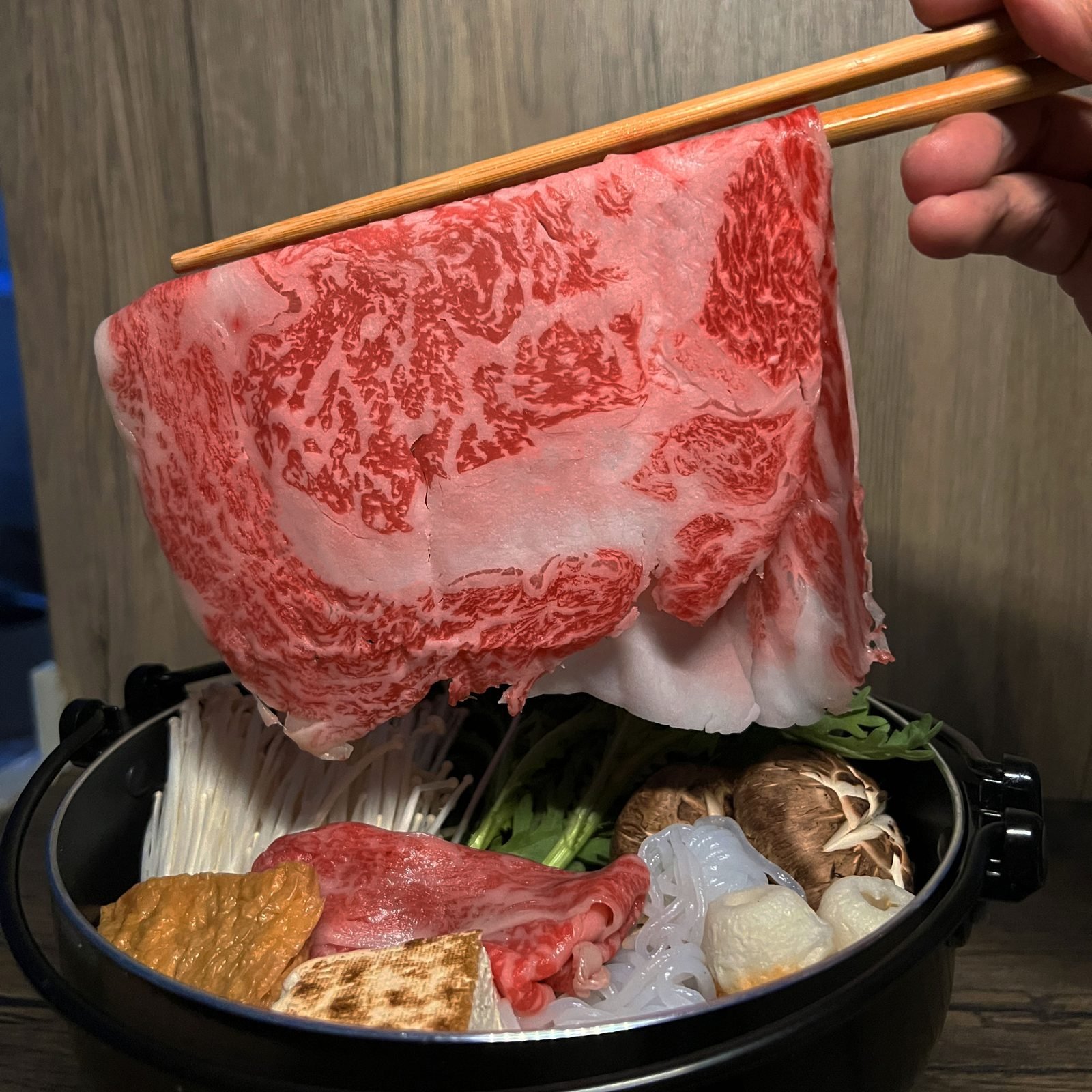 用筷子夾起陸奧牛壽喜燒片,下面係壽喜燒鍋